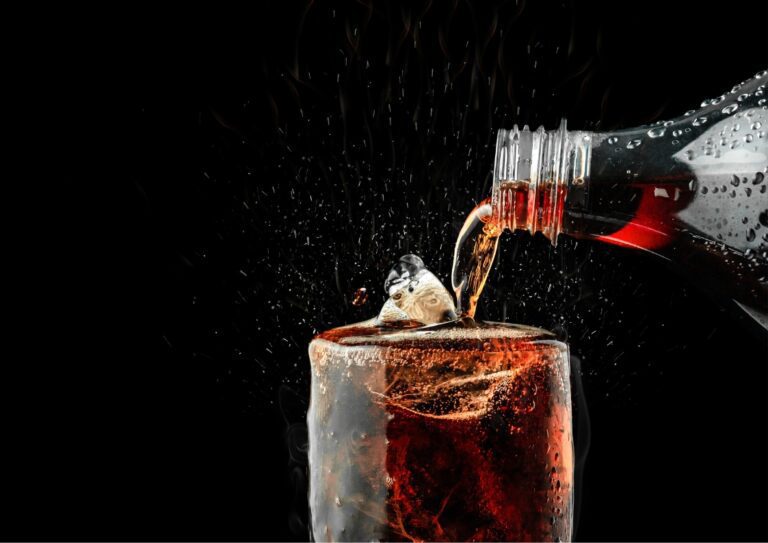 Uit een fles wordt cola geschonken in een glas